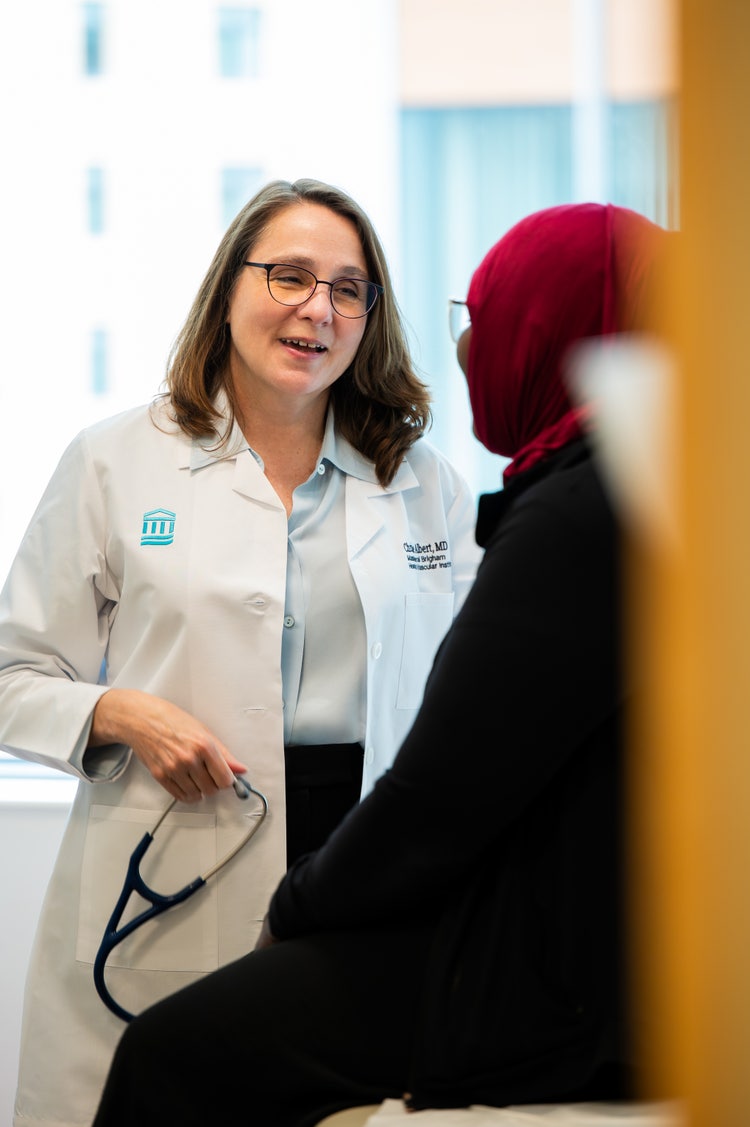 Doctor holds a stethoscope while talking with a patient during a clinical appointment.